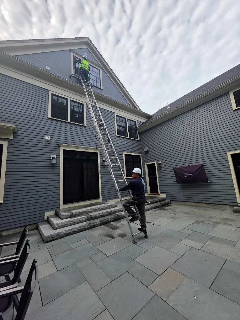 Sunbright Cleaning crew cleaning windows on a ladder at a Boston-area home